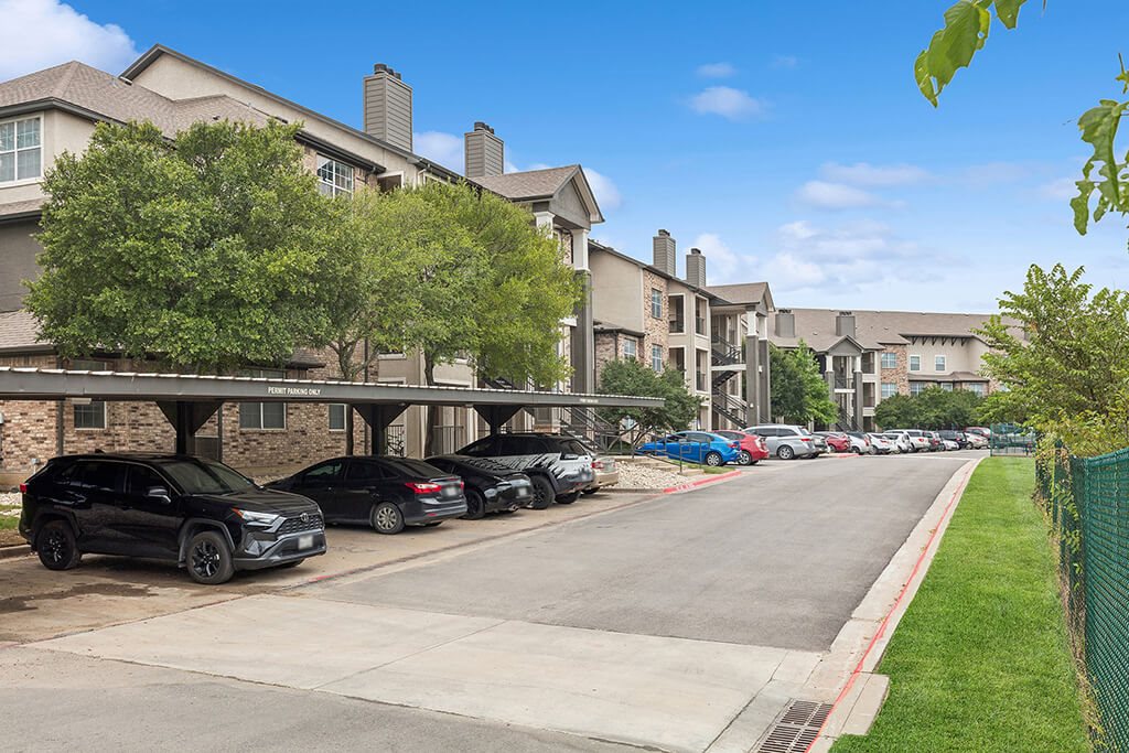 A row of cars parked in front of apartment buildings.